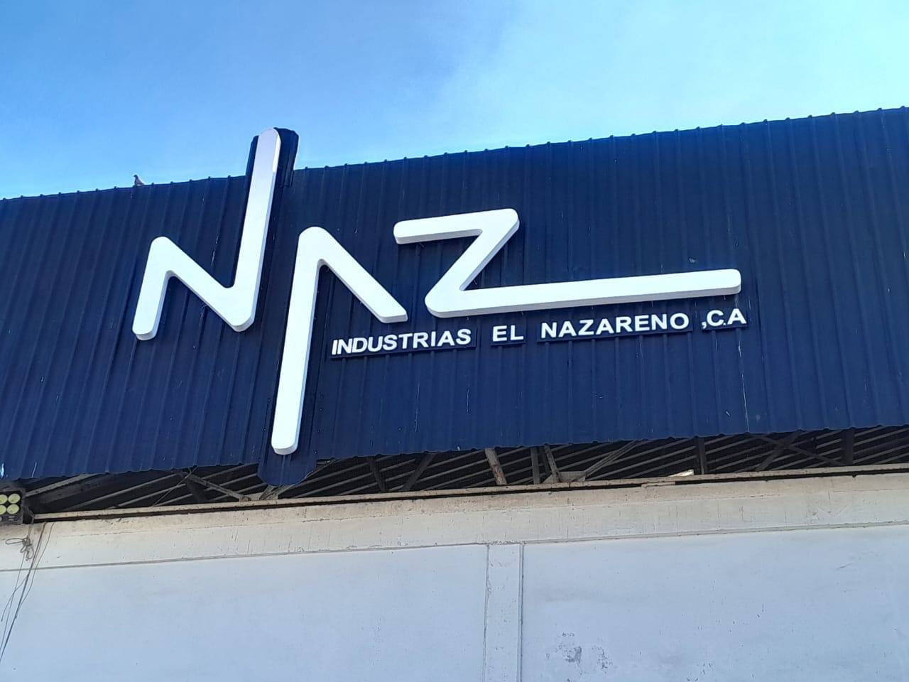 Letras corpóreas blancas NAZ sobre fachada azul
