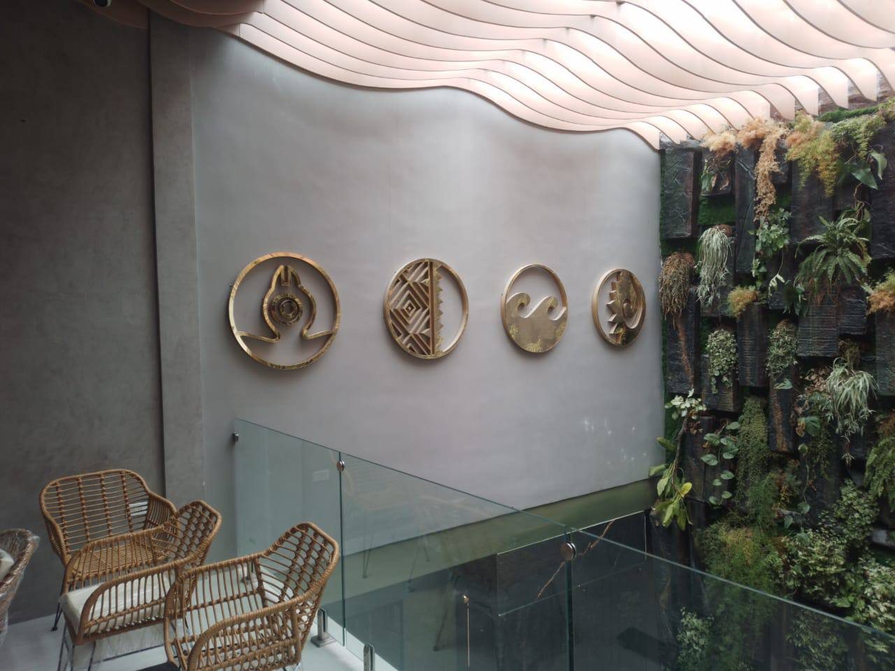 Cuatro piezas circulares en acero dorado sobre muro gris