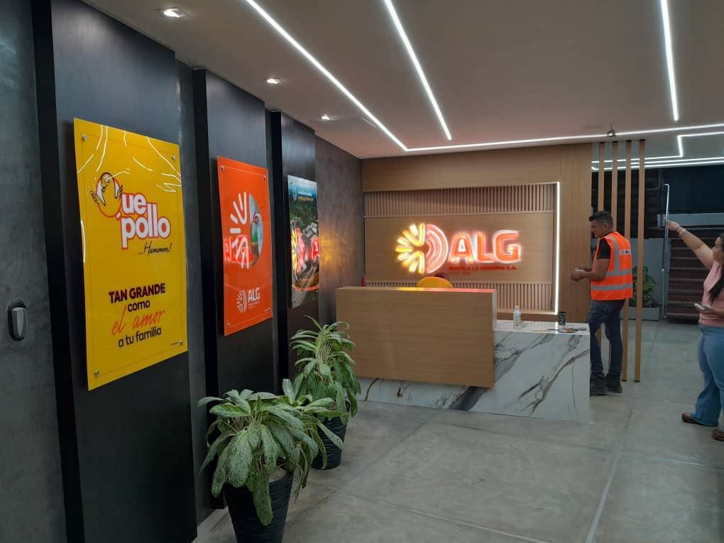 Recepción corporativa de ALG con logo luminoso y cuadros