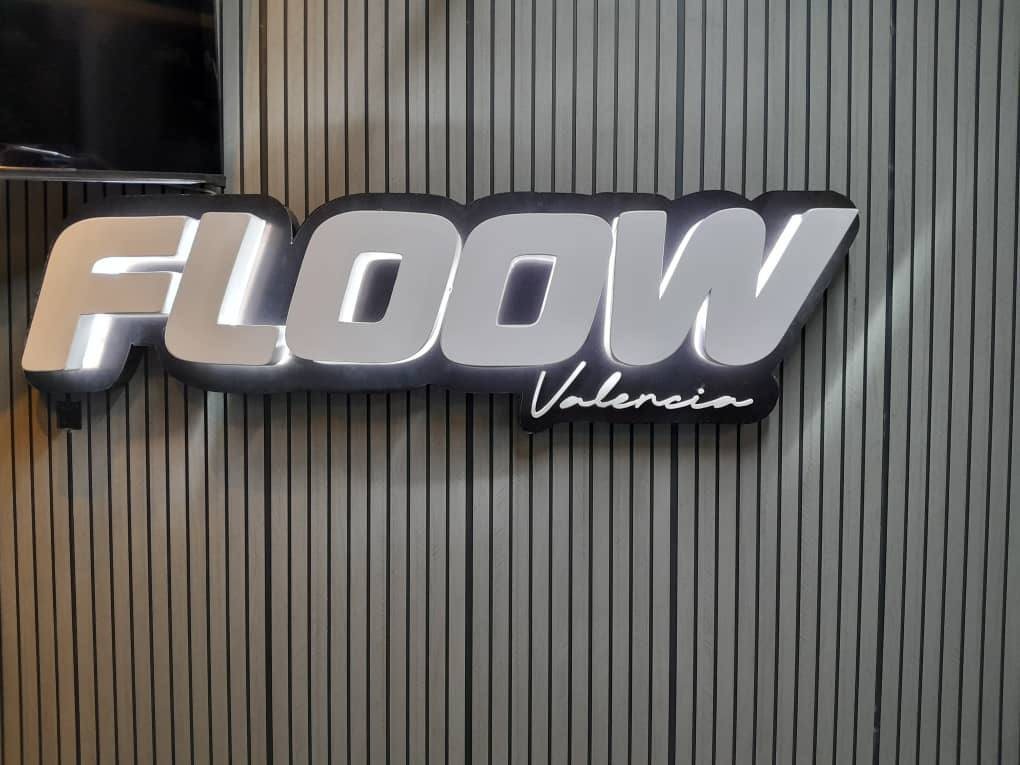 Logo retroiluminado Floow Valencia sobre panel ranurado