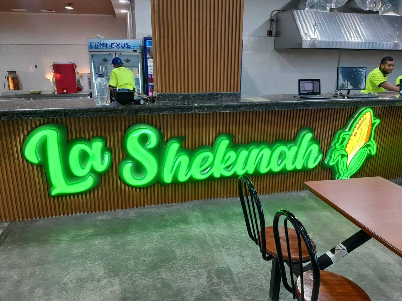 Letrero luminoso verde de La Shekinah en barra de madera