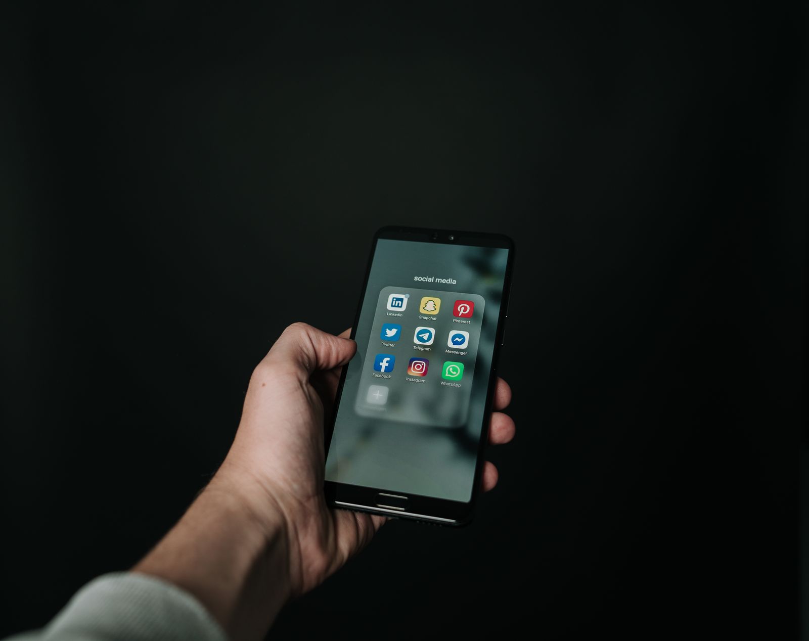 Smartphone con apps de redes sociales sobre fondo oscuro