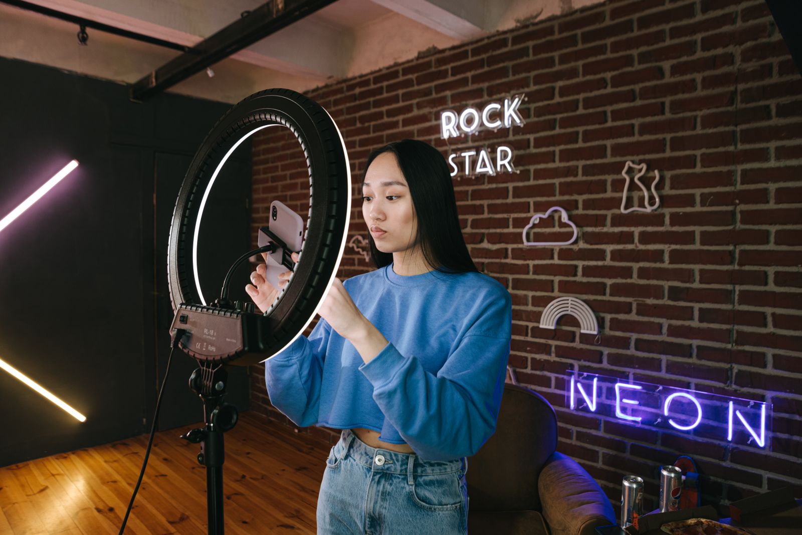 Creadora de contenido grabando con aro de luz en un estudio con neón