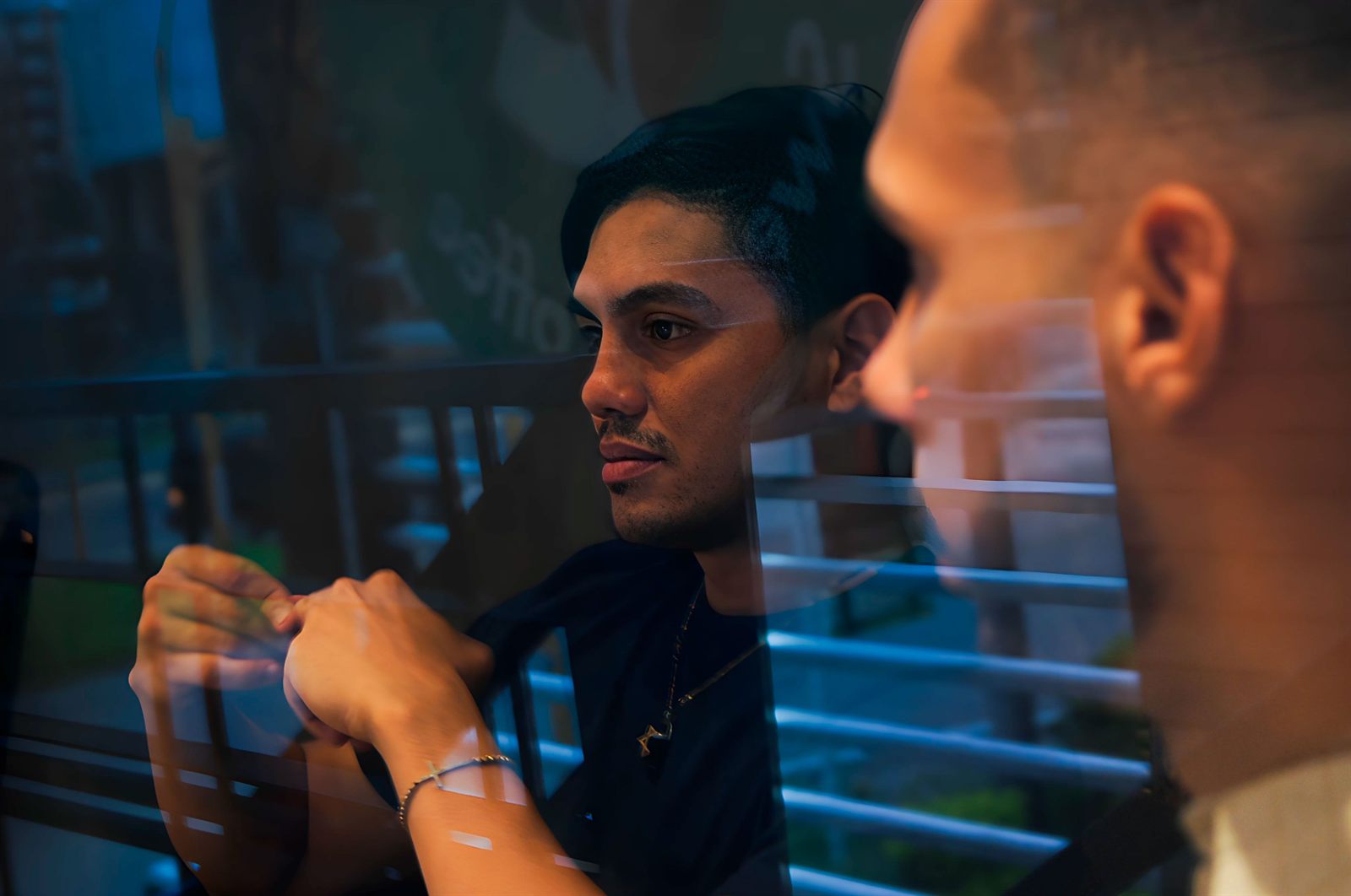 Fotografía cinematográfica de un hombre tras un cristal con reflejos